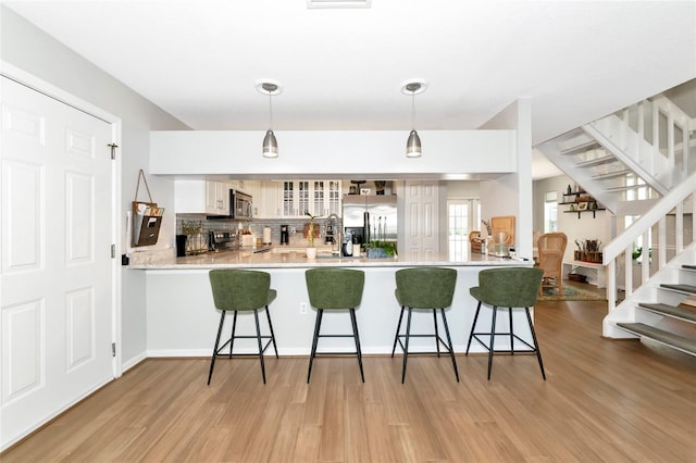 2311 64th Street Ct W, Bradenton, FL 34209 - kitchen featuring appliances with stainless steel finishes, a peninsula, light wood-style floors, and a breakfast bar area