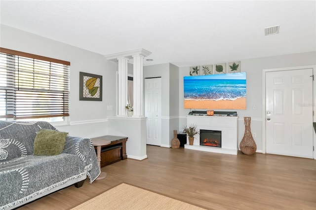 2311 64th Street Ct W, Bradenton, FL 34209 - living room with wood finished floors, a glass covered fireplace, baseboards, and decorative columns