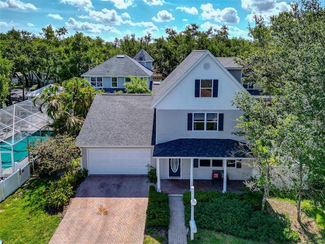 2311 64th Street Ct W, Bradenton, FL 34209 - traditional home with decorative driveway, a garage, a porch, glass enclosure, and a shingled roof