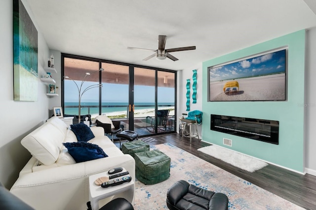 1310 Gulf Blvd Unit 6C, Clearwater Beach, FL 33767 - living area with a wall of windows, a ceiling fan, wood finished floors, a water view, and a glass covered fireplace