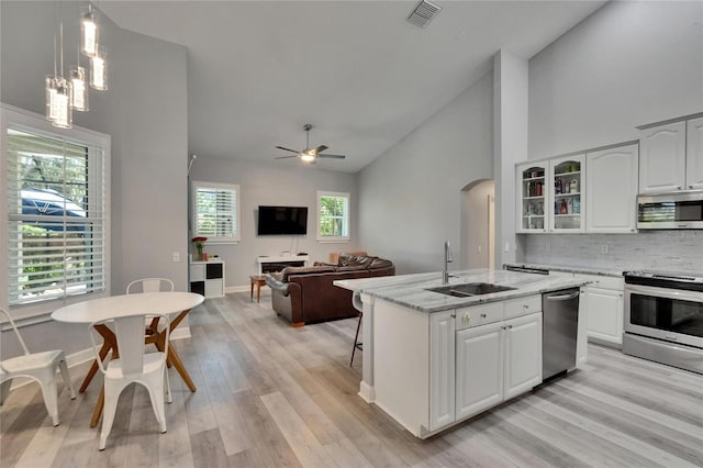 16367 Ashington Park Dr, Tampa, FL 33647 - kitchen with appliances with stainless steel finishes, a sink, arched walkways, light wood-style floors, and light stone counters