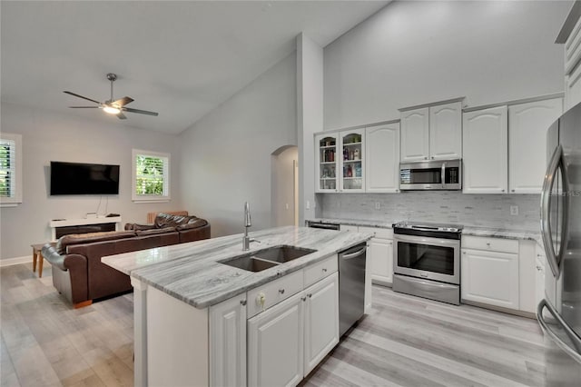 16367 Ashington Park Dr, Tampa, FL 33647 - kitchen with a sink, appliances with stainless steel finishes, arched walkways, decorative backsplash, and light wood-style flooring