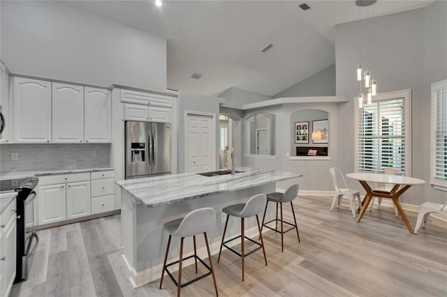 16367 Ashington Park Dr, Tampa, FL 33647 - kitchen with stainless steel fridge, electric stove, high vaulted ceiling, a sink, and light stone countertops