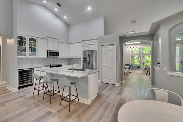 16367 Ashington Park Dr, Tampa, FL 33647 - kitchen featuring stainless steel appliances, wine cooler, arched walkways, a sink, and white cabinetry