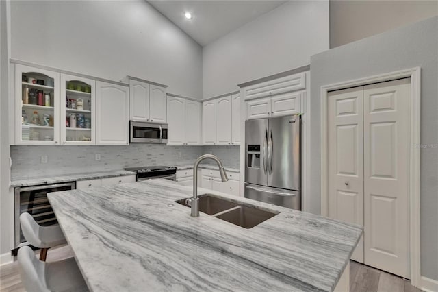 16367 Ashington Park Dr, Tampa, FL 33647 - kitchen featuring appliances with stainless steel finishes, a sink, high vaulted ceiling, beverage cooler, and light stone counters