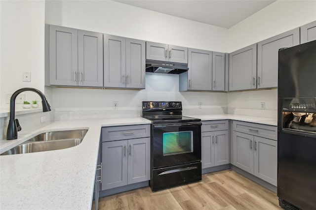 105 1st Ave SE, Lutz, FL 33549 - kitchen with black appliances, gray cabinets, a sink, under cabinet range hood, and light wood-type flooring