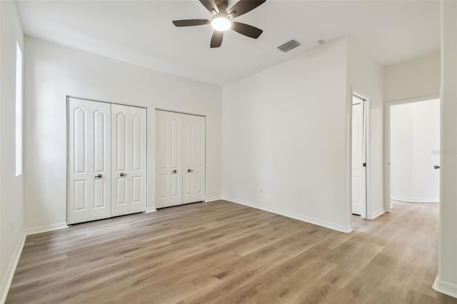 105 1st Ave SE, Lutz, FL 33549 - unfurnished bedroom with multiple closets, light wood finished floors, baseboards, and ceiling fan