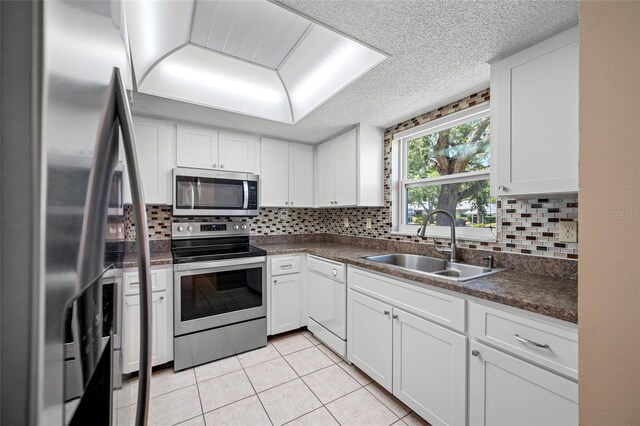 70 Cypress Pl, Oldsmar, FL 34677 - kitchen featuring appliances with stainless steel finishes, a sink, dark countertops, tasteful backsplash, and a textured ceiling