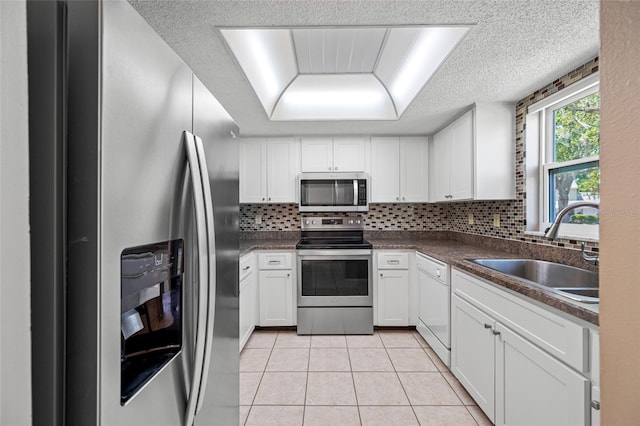 70 Cypress Pl, Oldsmar, FL 34677 - kitchen featuring appliances with stainless steel finishes, a sink, white cabinetry, tasteful backsplash, and a textured ceiling