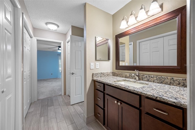 70 Cypress Pl, Oldsmar, FL 34677 - bathroom featuring vanity, a ceiling fan, a textured ceiling, and baseboards