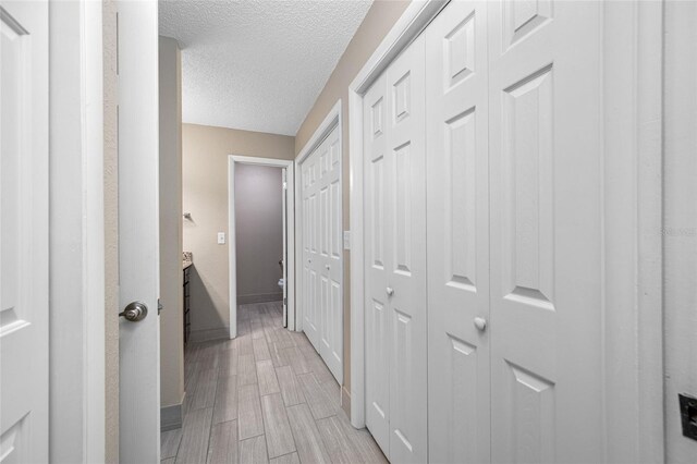 70 Cypress Pl, Oldsmar, FL 34677 - hallway with a textured ceiling, baseboards, and light wood finished floors