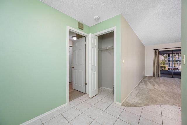 70 Cypress Pl, Oldsmar, FL 34677 - unfurnished bedroom with a textured ceiling, baseboards, a closet, light tile patterned floors, and light colored carpet