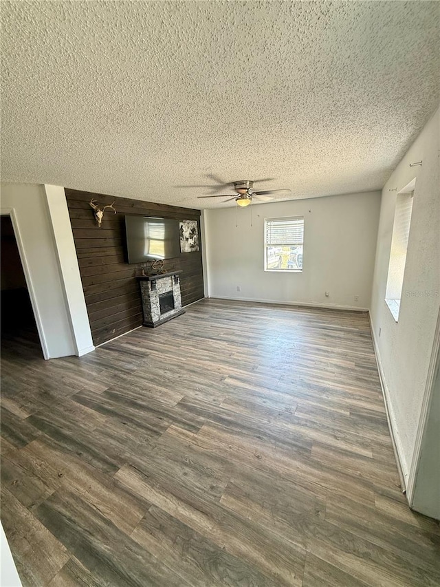439 Corbett Rd, Lithia, FL 33547 - unfurnished living room with a textured ceiling, a stone fireplace, ceiling fan, dark wood-type flooring, and baseboards