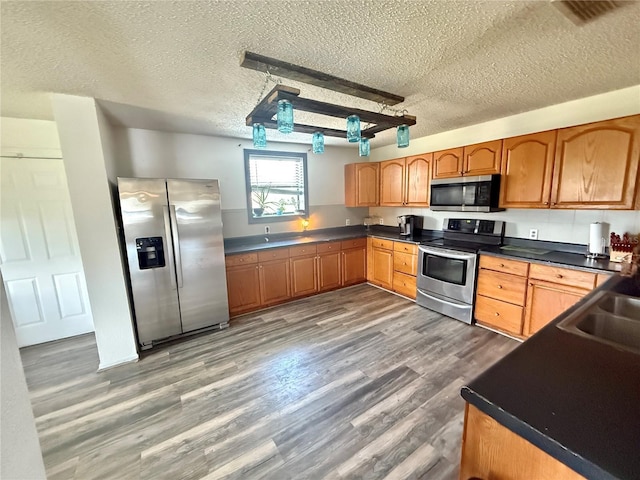 439 Corbett Rd, Lithia, FL 33547 - kitchen with appliances with stainless steel finishes, a textured ceiling, dark countertops, dark wood finished floors, and brown cabinetry
