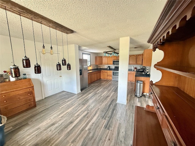 439 Corbett Rd, Lithia, FL 33547 - kitchen with stainless steel appliances, dark countertops, a textured ceiling, wood finished floors, and a sink