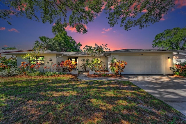 1766 Hitching Post Ln, Dunedin, FL 34698 - view of front of home with stucco siding, a garage, concrete driveway, and a yard
