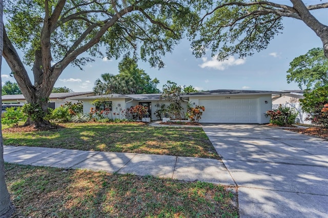 1766 Hitching Post Ln, Dunedin, FL 34698 - ranch-style home featuring a garage, stucco siding, concrete driveway, and a front lawn