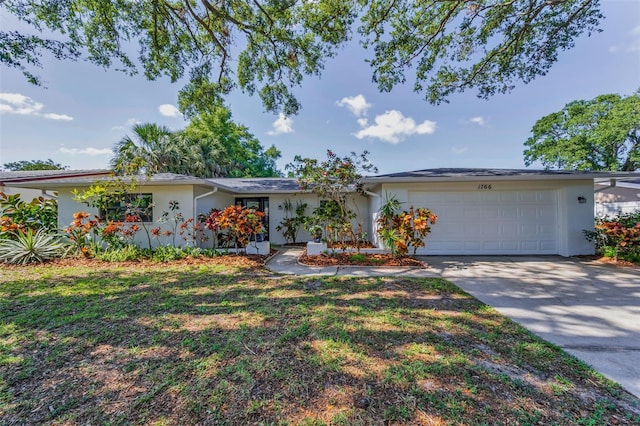 1766 Hitching Post Ln, Dunedin, FL 34698 - view of front of home featuring stucco siding, a garage, concrete driveway, and a front lawn