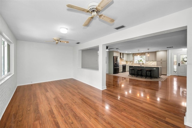 1766 Hitching Post Ln, Dunedin, FL 34698 - unfurnished living room featuring a ceiling fan, healthy amount of natural light, wood finished floors, and baseboards