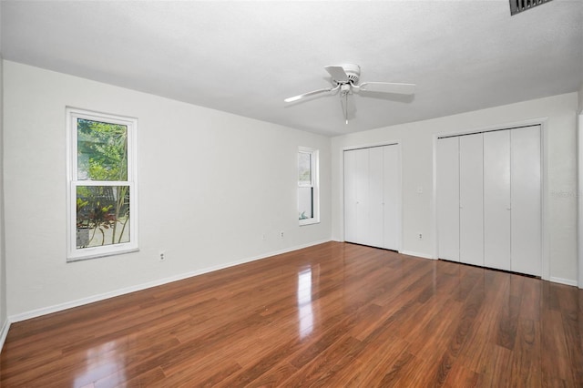 1766 Hitching Post Ln, Dunedin, FL 34698 - unfurnished bedroom with two closets, wood finished floors, baseboards, and ceiling fan