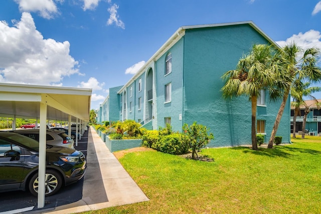 255 114th Ave N Unit 4, Saint Petersburg, FL 33716 - view of home's exterior featuring a lawn, stucco siding, and covered parking