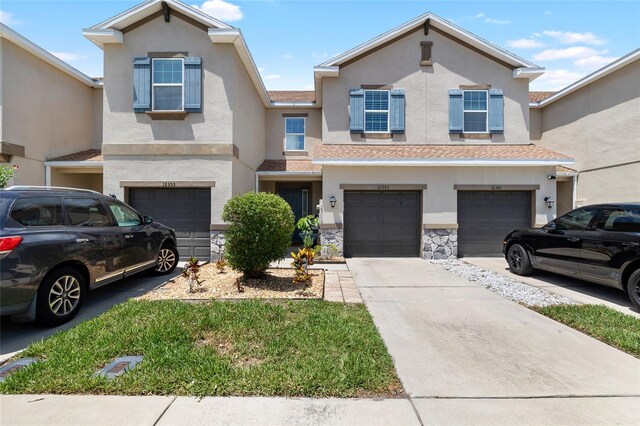 12353 Bayou Flats Ln, Tampa, FL 33635 - townhome / multi-family property featuring a garage, stucco siding, driveway, and stone siding