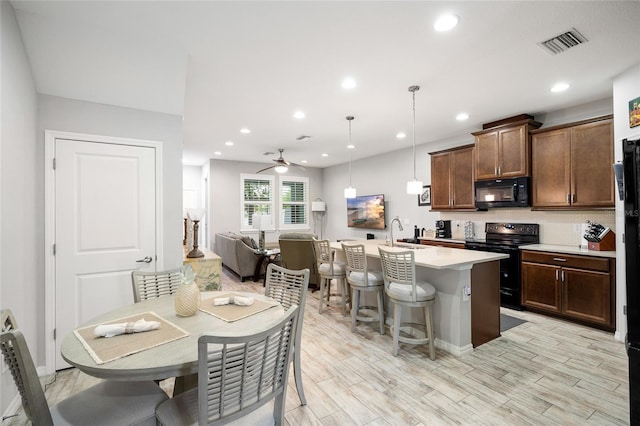 12353 Bayou Flats Ln, Tampa, FL 33635 - kitchen featuring black appliances, light countertops, a kitchen breakfast bar, a sink, and an island with sink