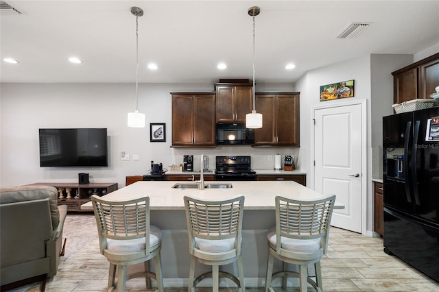 12353 Bayou Flats Ln, Tampa, FL 33635 - kitchen with black appliances, a sink, open floor plan, dark brown cabinets, and light countertops