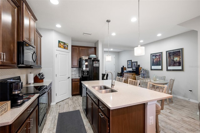 12353 Bayou Flats Ln, Tampa, FL 33635 - kitchen featuring black appliances, a sink, decorative backsplash, light wood-style flooring, and recessed lighting