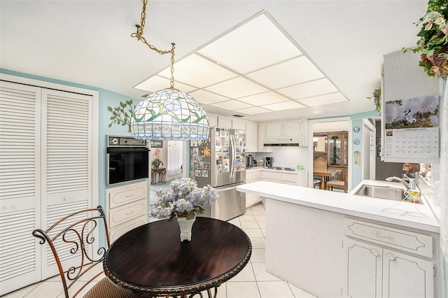 10400 112th Way, Largo, FL 33778 - kitchen with black oven, a peninsula, stainless steel fridge with ice dispenser, a sink, and light tile patterned flooring