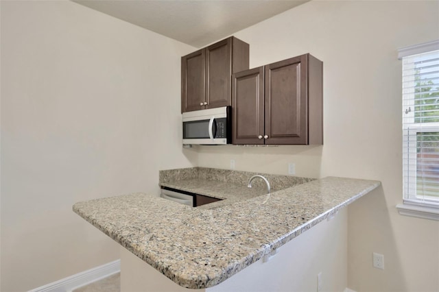 1229 Hillandale Reserve Dr, Tampa, FL 33613 - kitchen with dark brown cabinetry, a peninsula, and light stone counters