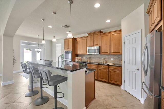 1229 Hillandale Reserve Dr, Tampa, FL 33613 - kitchen with appliances with stainless steel finishes, brown cabinetry, backsplash, a kitchen bar, and recessed lighting