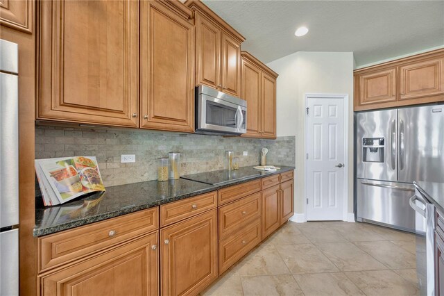 1229 Hillandale Reserve Dr, Tampa, FL 33613 - kitchen featuring appliances with stainless steel finishes, decorative backsplash, brown cabinetry, dark stone counters, and light tile patterned floors