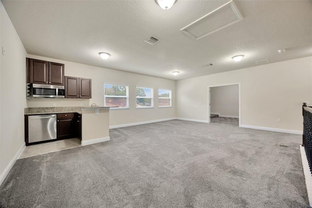 1229 Hillandale Reserve Dr, Tampa, FL 33613 - kitchen featuring stainless steel appliances, open floor plan, light carpet, dark brown cabinetry, and a textured ceiling