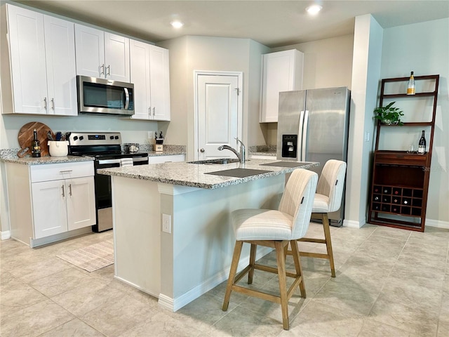 2717 Chestnut Creek Pl, Brandon, FL 33510 - kitchen featuring appliances with stainless steel finishes, a sink, a kitchen island with sink, light stone countertops, and white cabinets