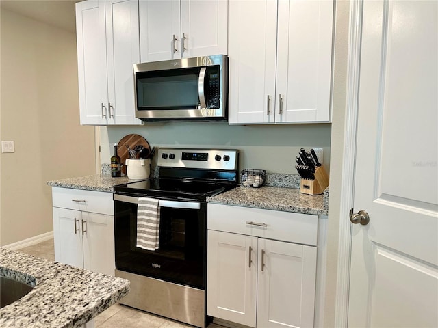 2717 Chestnut Creek Pl, Brandon, FL 33510 - kitchen featuring appliances with stainless steel finishes, white cabinetry, light stone countertops, and light tile patterned flooring