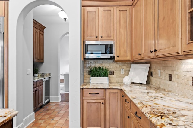 7713 Still Lakes Dr, Odessa, FL 33556 - kitchen featuring stainless steel microwave, arched walkways, beverage cooler, backsplash, and light tile patterned floors