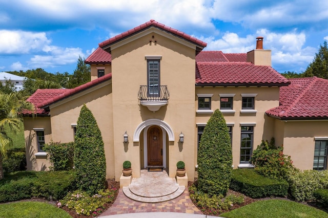 7713 Still Lakes Dr, Odessa, FL 33556 - mediterranean / spanish-style home featuring a balcony, a tiled roof, a chimney, and stucco siding