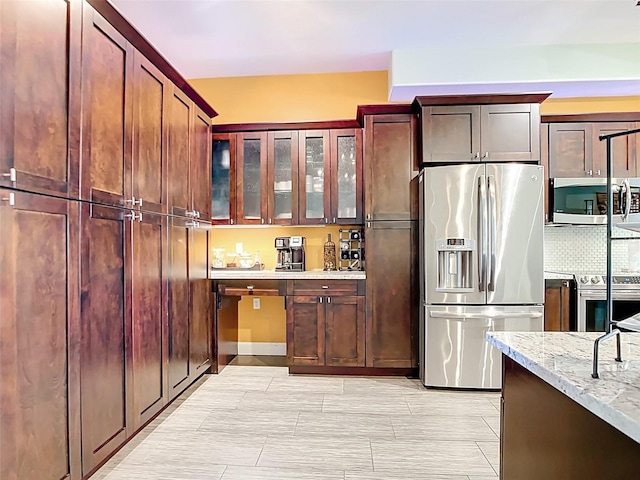 3334 Purple Martin Dr Unit 212, Punta Gorda, FL 33950 - kitchen with appliances with stainless steel finishes, light stone countertops, glass insert cabinets, and tasteful backsplash