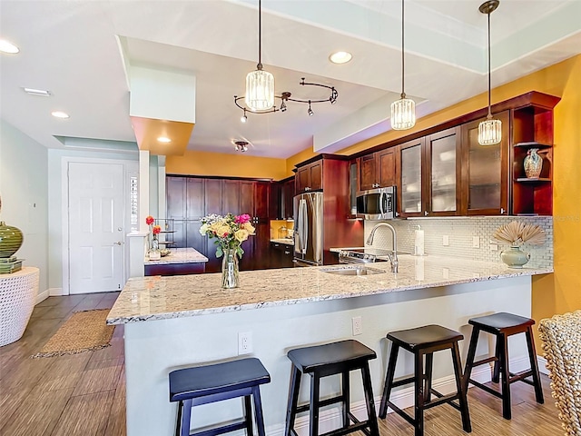 3334 Purple Martin Dr Unit 212, Punta Gorda, FL 33950 - kitchen featuring appliances with stainless steel finishes, a peninsula, decorative backsplash, light stone countertops, and hanging light fixtures