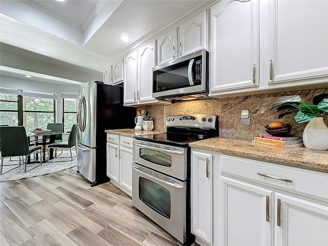 66 Bay Woods Dr, Safety Harbor, FL 34695 - kitchen featuring appliances with stainless steel finishes, white cabinetry, decorative backsplash, ornamental molding, and light stone countertops