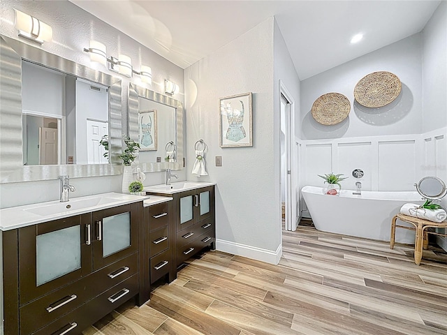 66 Bay Woods Dr, Safety Harbor, FL 34695 - full bath featuring double vanity, a soaking tub, wood finished floors, and lofted ceiling