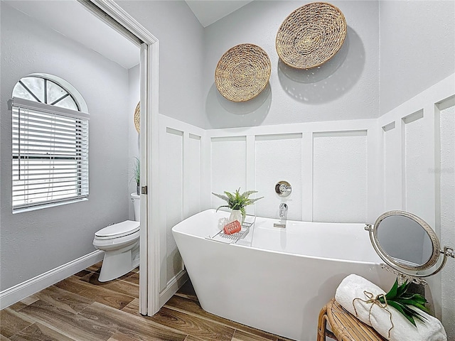 66 Bay Woods Dr, Safety Harbor, FL 34695 - bathroom with a freestanding tub, toilet, wood finished floors, wainscoting, and a decorative wall