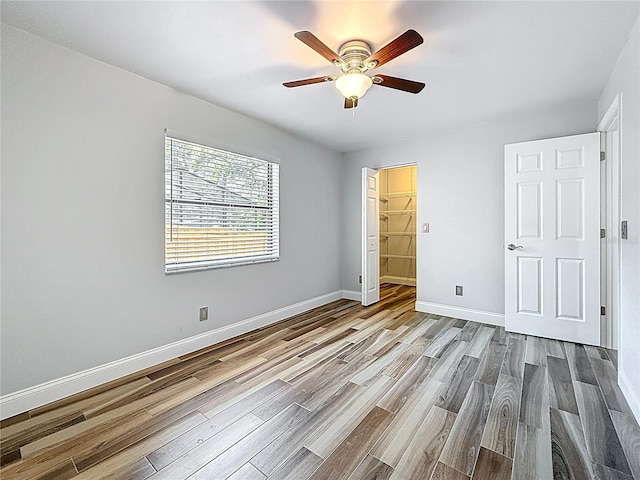 66 Bay Woods Dr, Safety Harbor, FL 34695 - unfurnished bedroom with wood finished floors, baseboards, ceiling fan, and a spacious closet