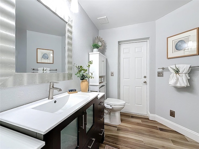 66 Bay Woods Dr, Safety Harbor, FL 34695 - bathroom with toilet, vanity, wood finished floors, and baseboards