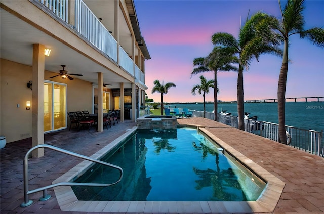 514 Harbor Dr N, Indian Rocks Beach, FL 33785 - pool at dusk with ceiling fan, a water view, a patio, and a pool with connected hot tub