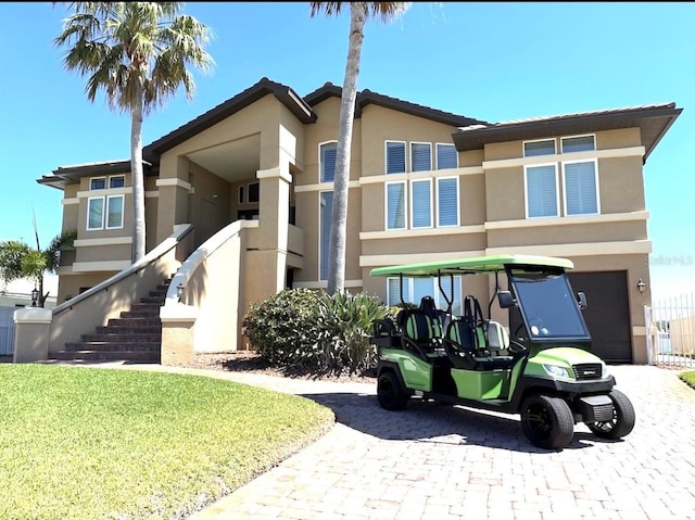 514 Harbor Dr N, Indian Rocks Beach, FL 33785 - view of front of property featuring stucco siding, an attached garage, driveway, stairs, and a front lawn