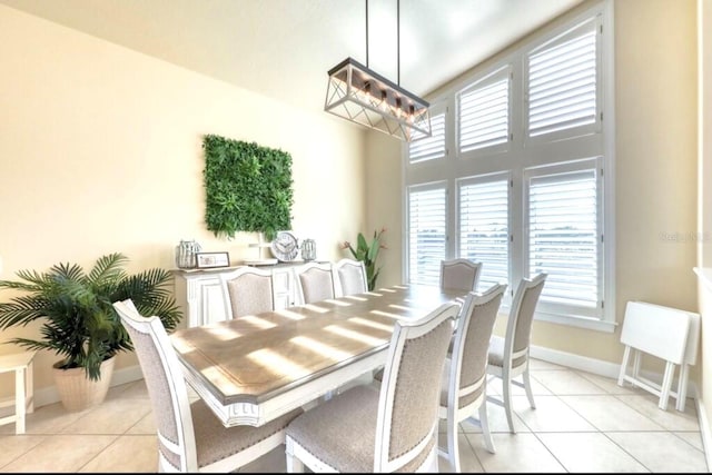514 Harbor Dr N, Indian Rocks Beach, FL 33785 - dining area with light tile patterned floors, baseboards, a towering ceiling, and a chandelier