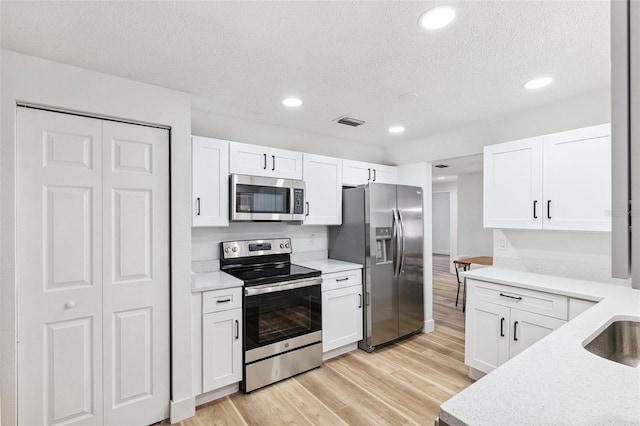 622 Cedar Grove Dr, Brandon, FL 33511 - kitchen with stainless steel appliances, a textured ceiling, light wood finished floors, light countertops, and white cabinets