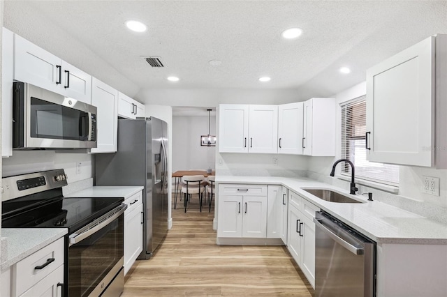 622 Cedar Grove Dr, Brandon, FL 33511 - kitchen featuring appliances with stainless steel finishes, a sink, light wood-style flooring, white cabinets, and recessed lighting